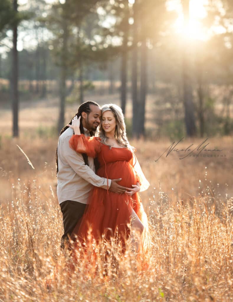 A couple during their maternity session in a wheat field at golden hour 